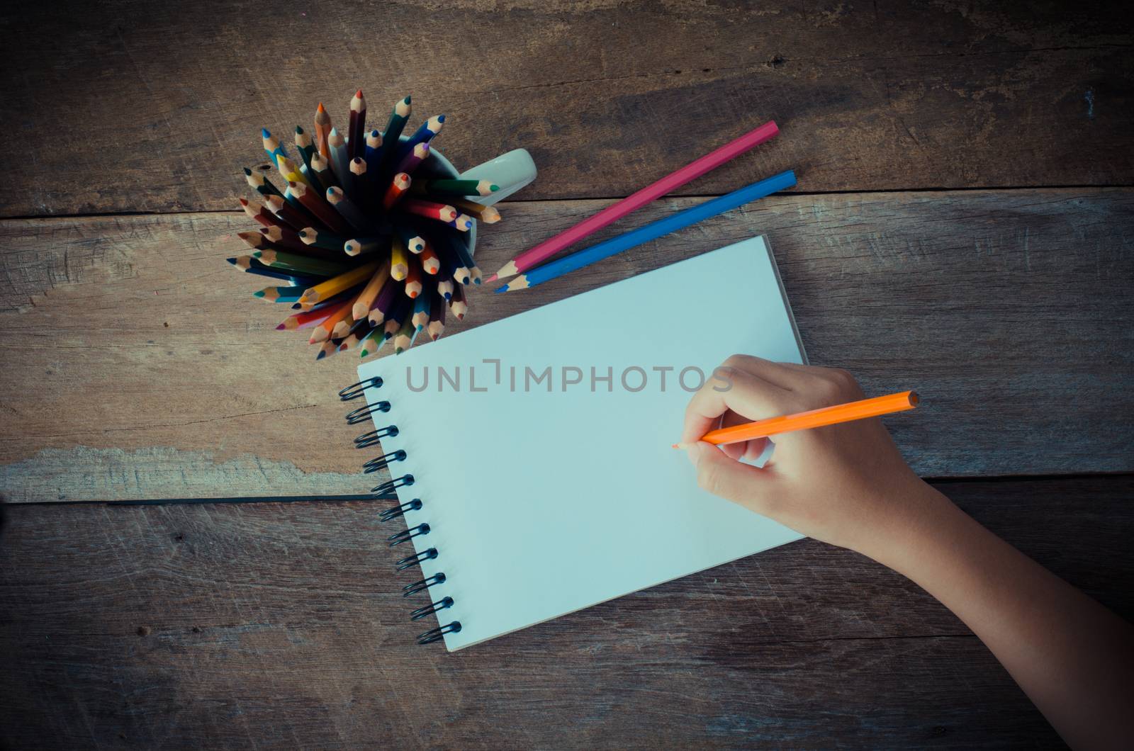 Hand writing in open notebook on table