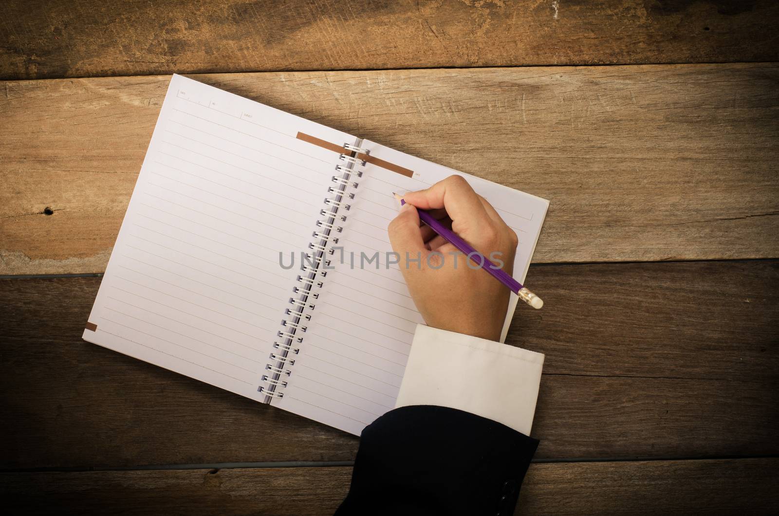 Hand writing in open notebook on table