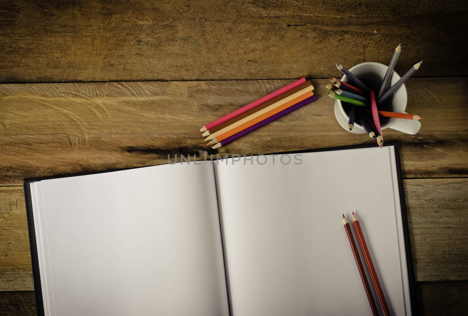 Color pencil and sketchbook on wood table