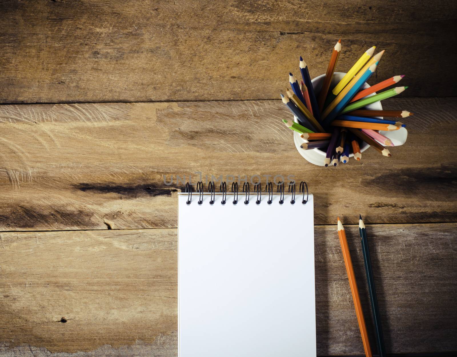 Color pencil and sketchbook on wood table by photobyphotoboy