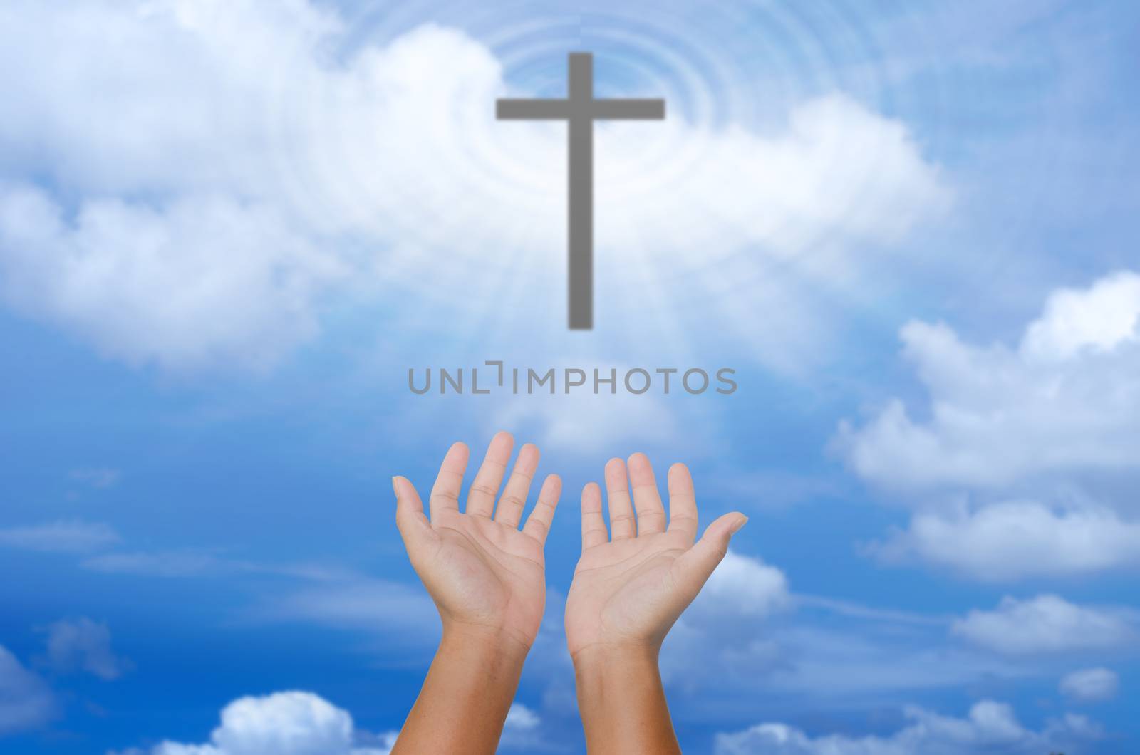 open hands praying the cross on blur sky background.