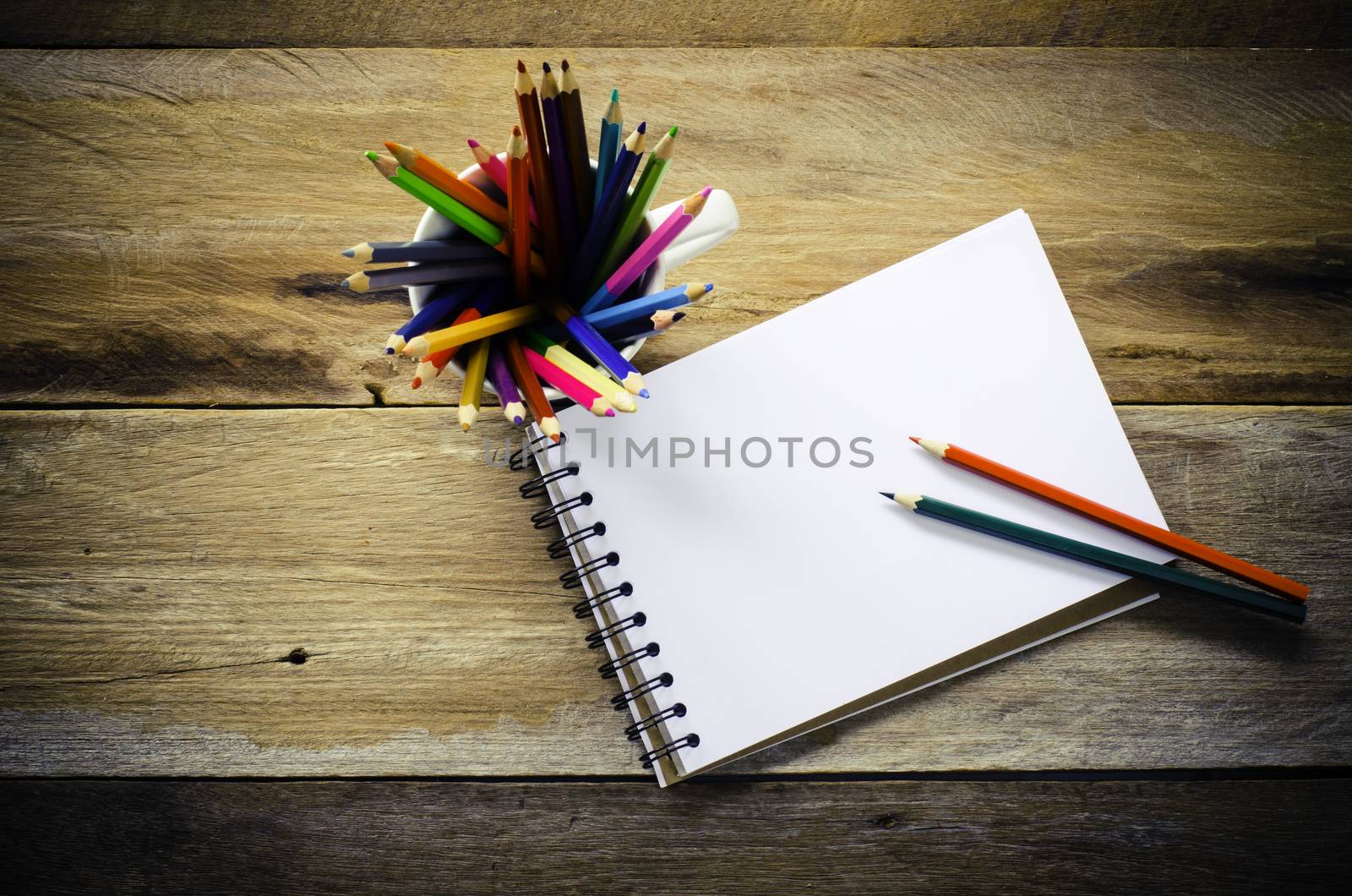 Color pencil and sketchbook on wood table by photobyphotoboy