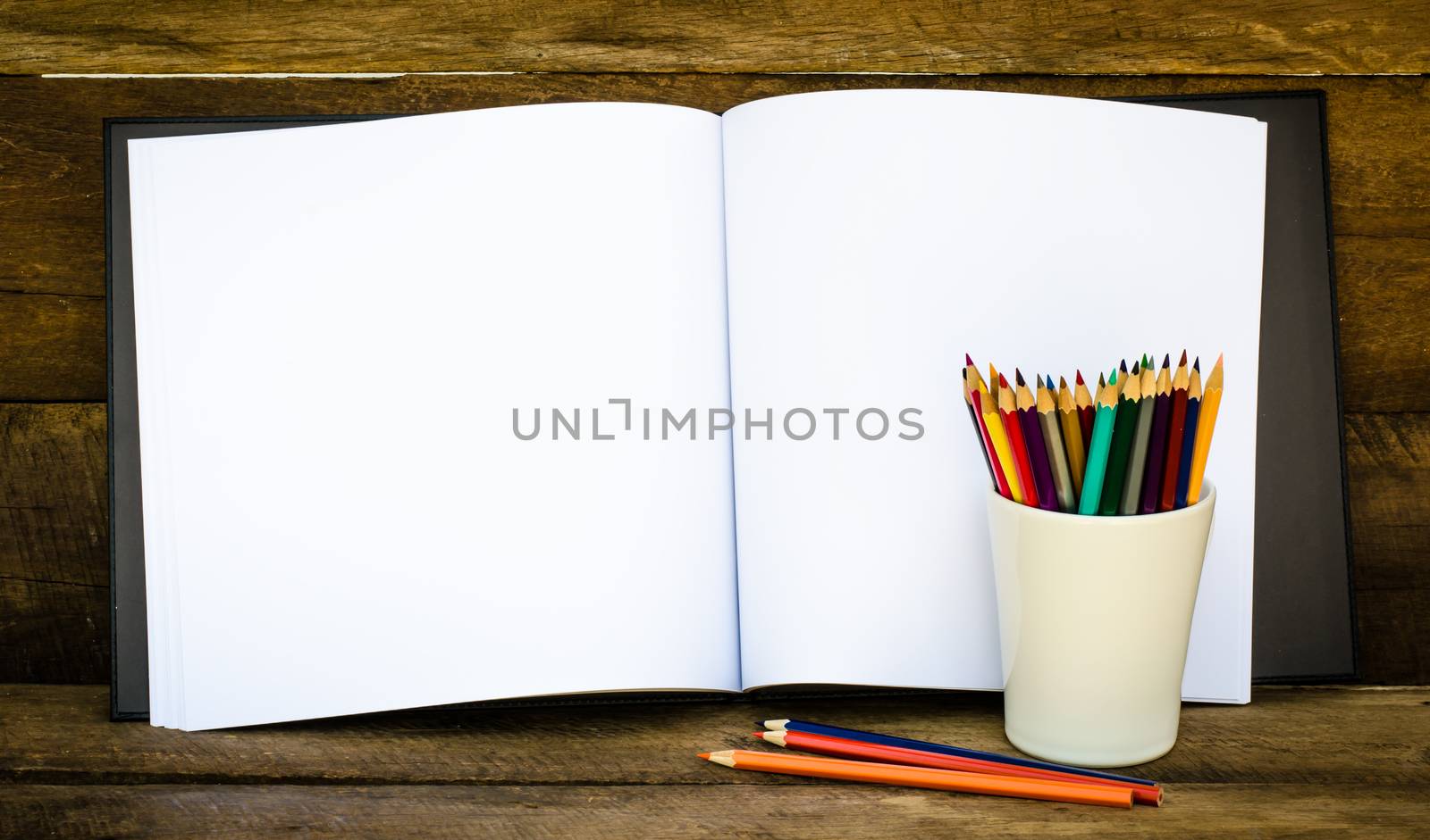 Color pencil and sketchbook on wooden background by photobyphotoboy