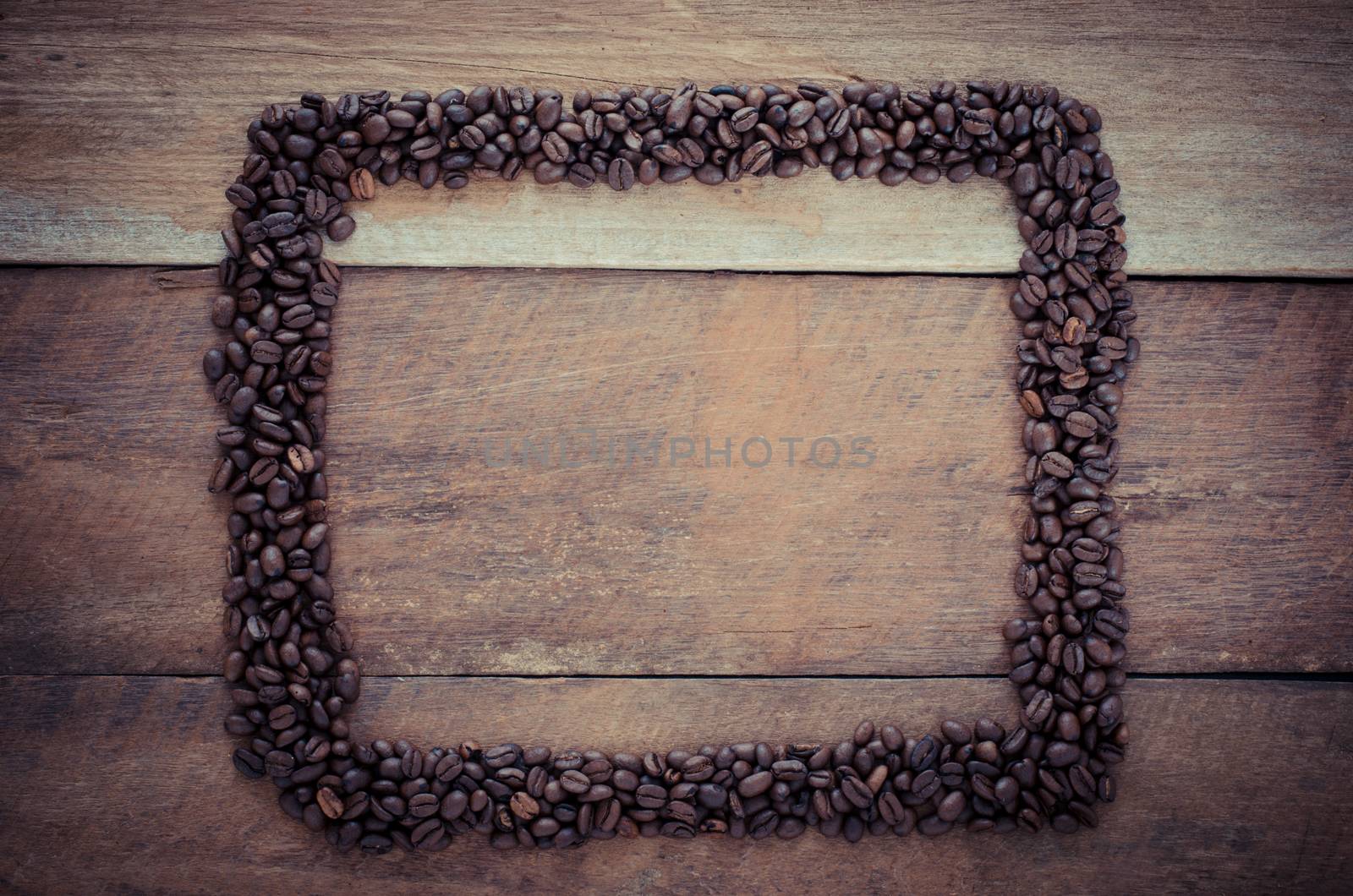 Rectangle frame made of coffee beans on the wooden background by photobyphotoboy