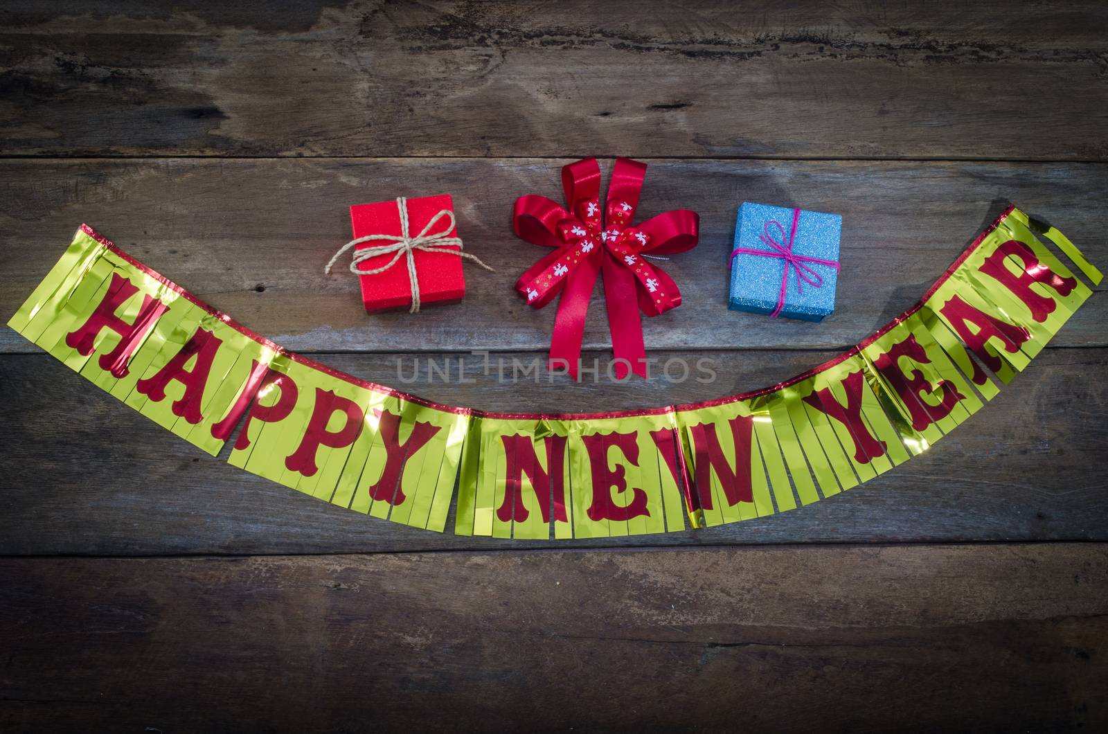 happy New Year message and gift box on wooden background. by photobyphotoboy