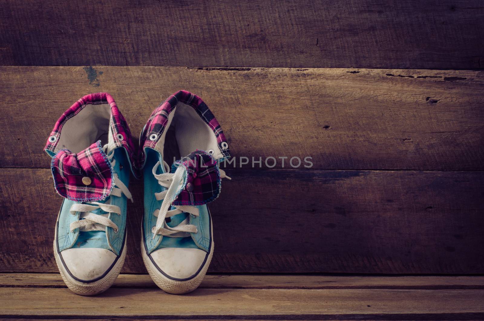 Sneakers on floor on wooden background by photobyphotoboy