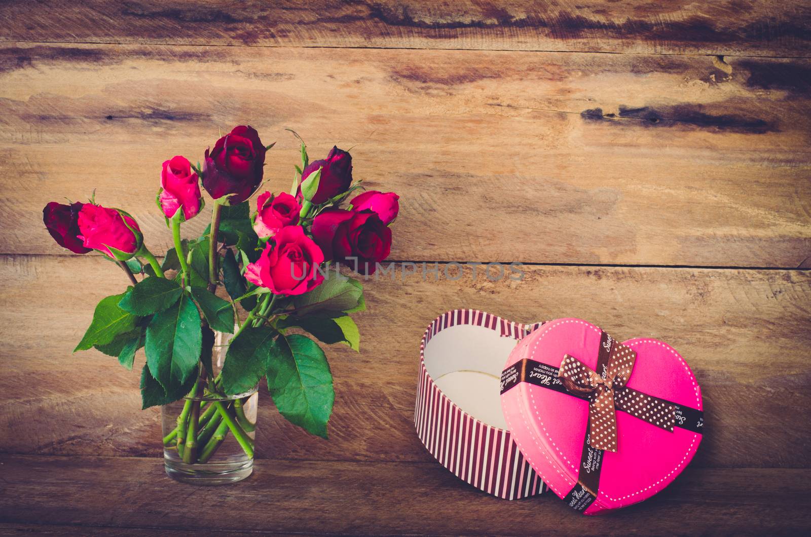 Red roses in glass and Heart shaped Valentine's Day gift box on  by photobyphotoboy