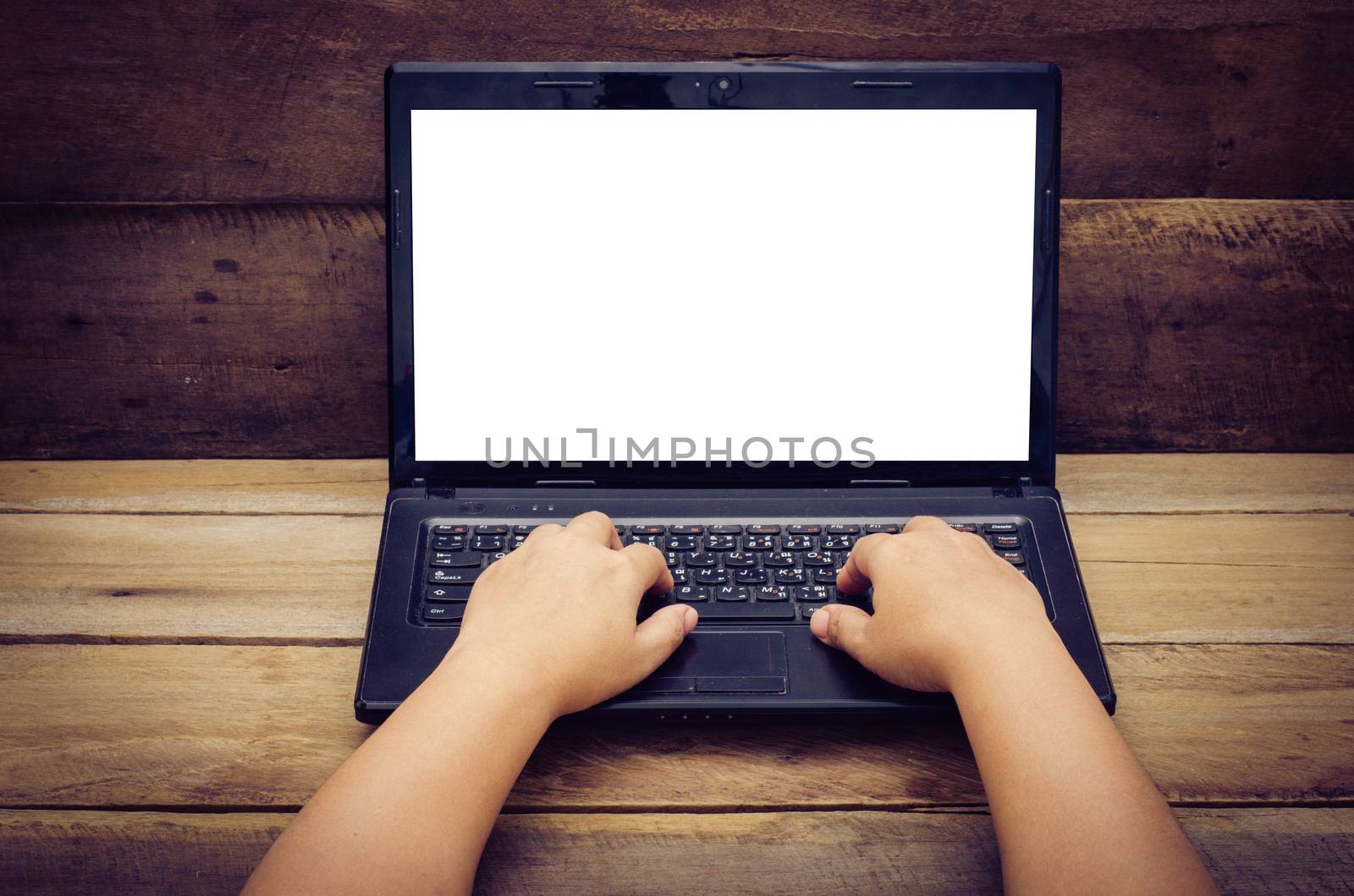 hands typing on laptop on wooden background by photobyphotoboy