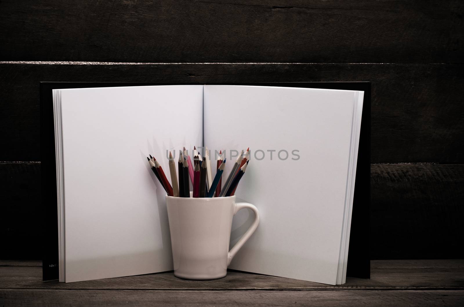 Color pencil and sketchbook on wooden background by photobyphotoboy