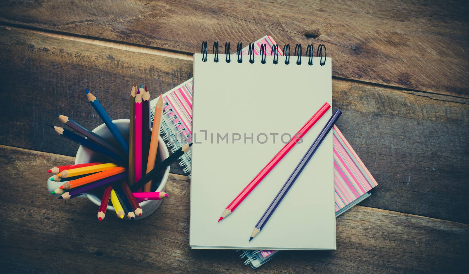 Color pencil and sketchbook on wooden background by photobyphotoboy