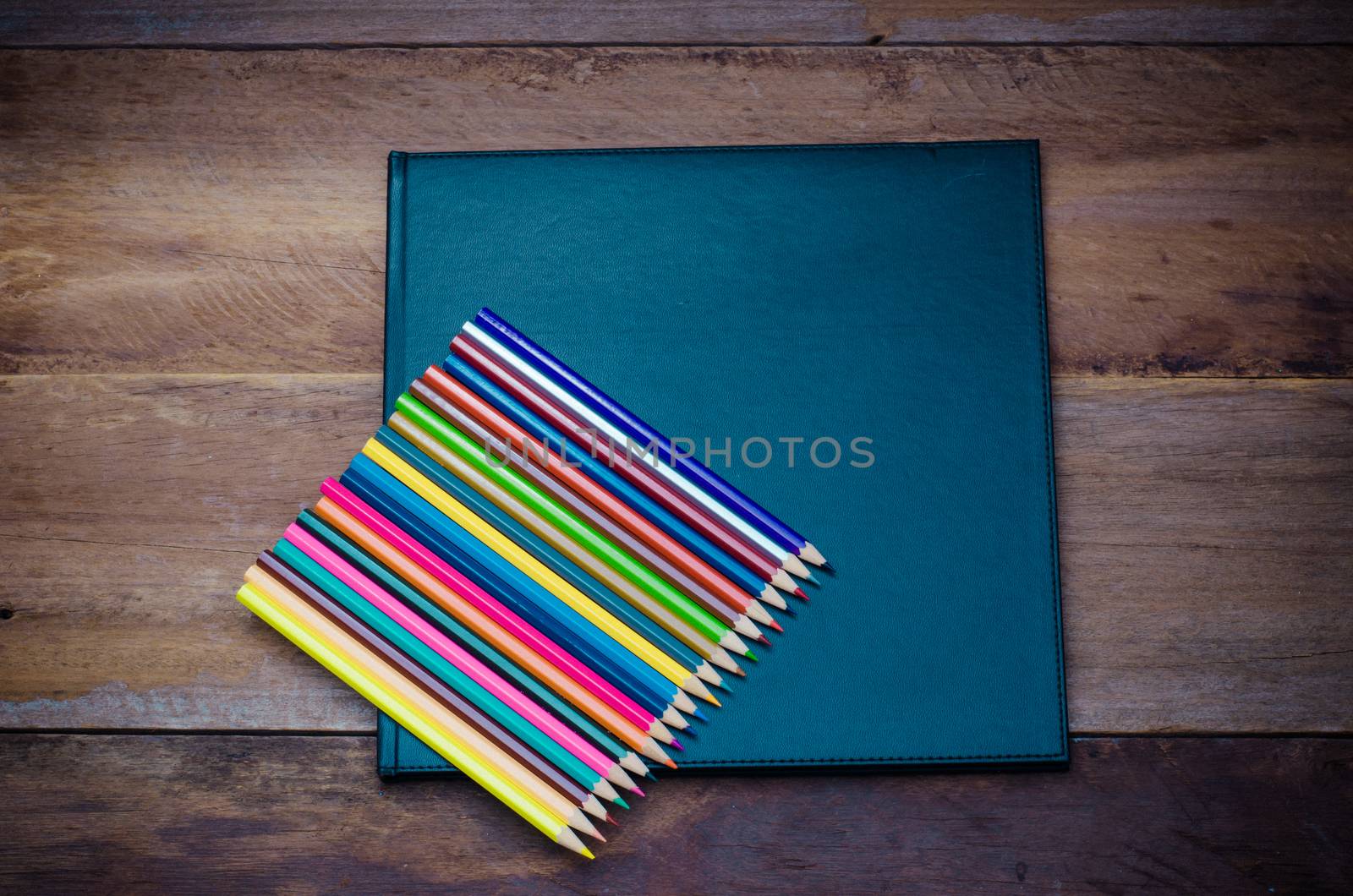 Color pencil and sketchbook on wooden background by photobyphotoboy