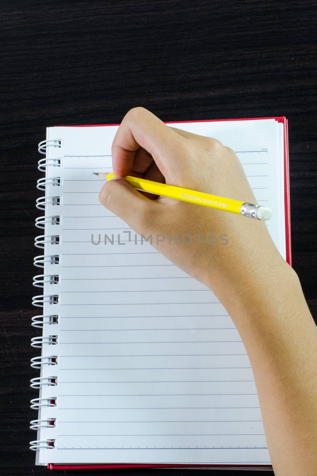Hand writing in open notebook on table by photobyphotoboy