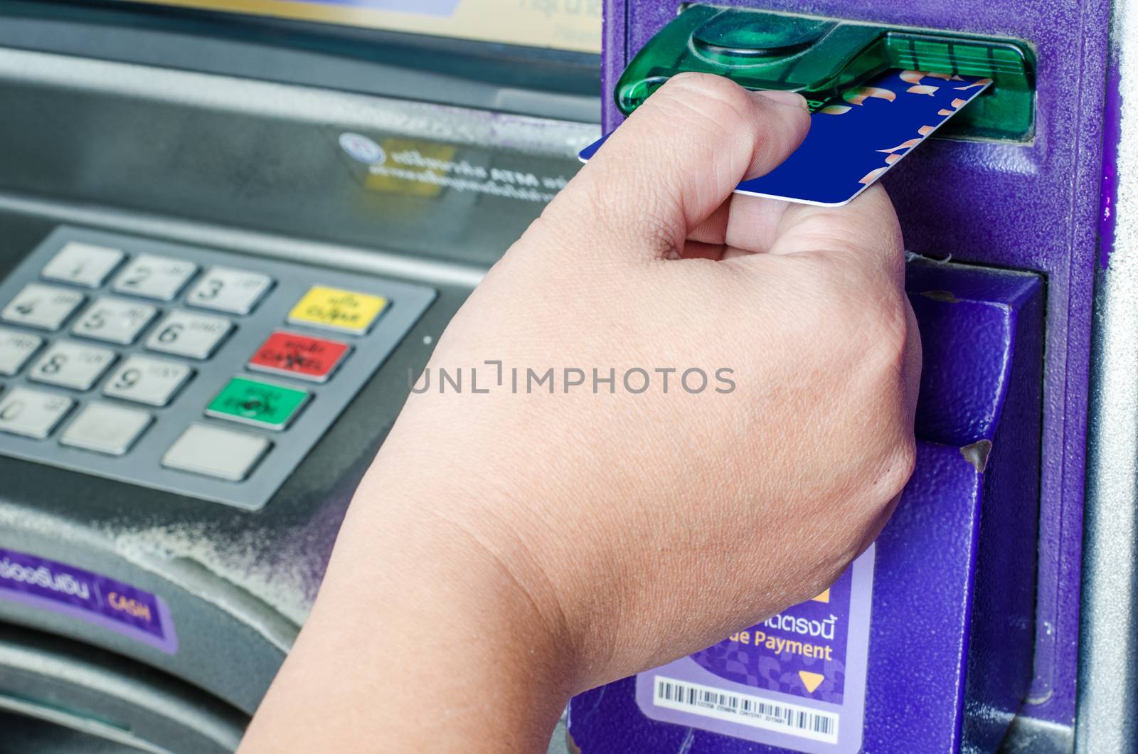 Hand inserting ATM credit card into bank machine  by photobyphotoboy