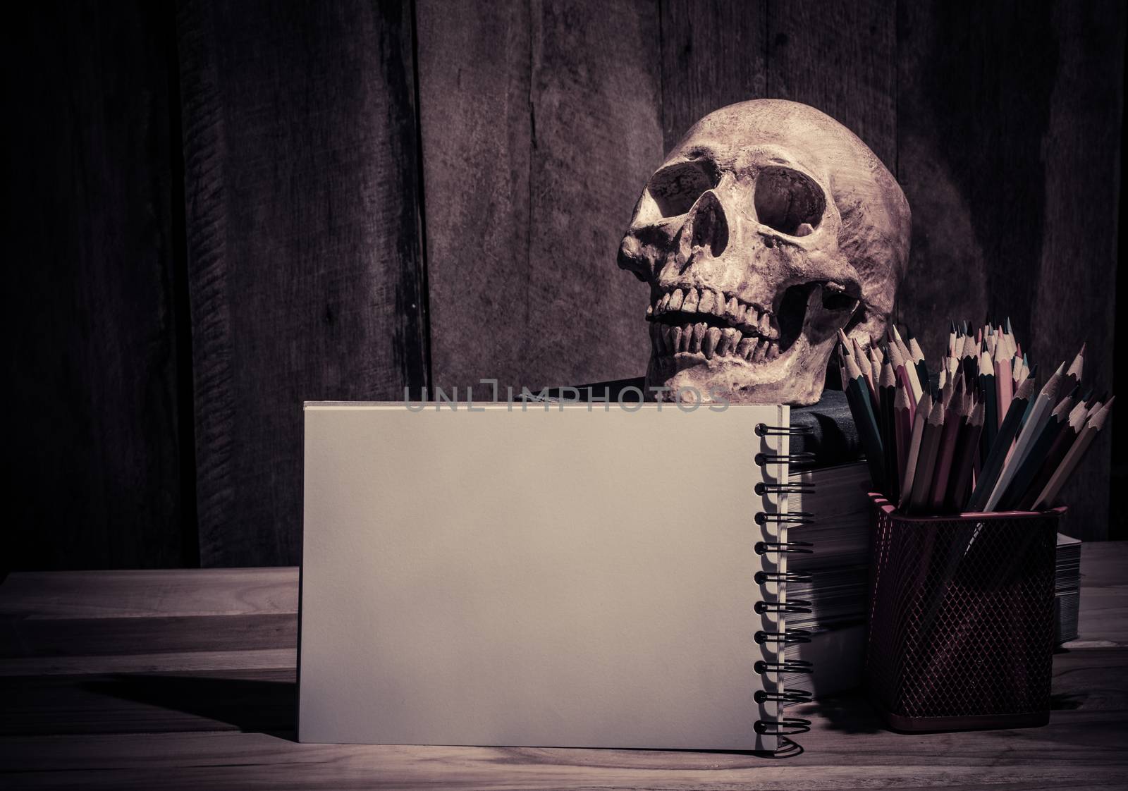 still life Color pencil sketchbook and skull on wooden background