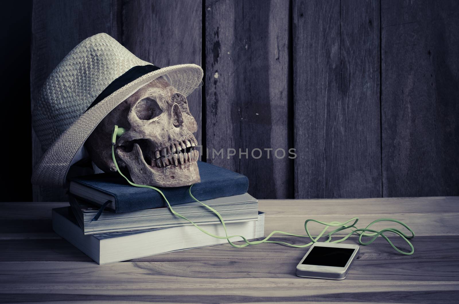 still life - skull have headphone on books and hat on wooden table