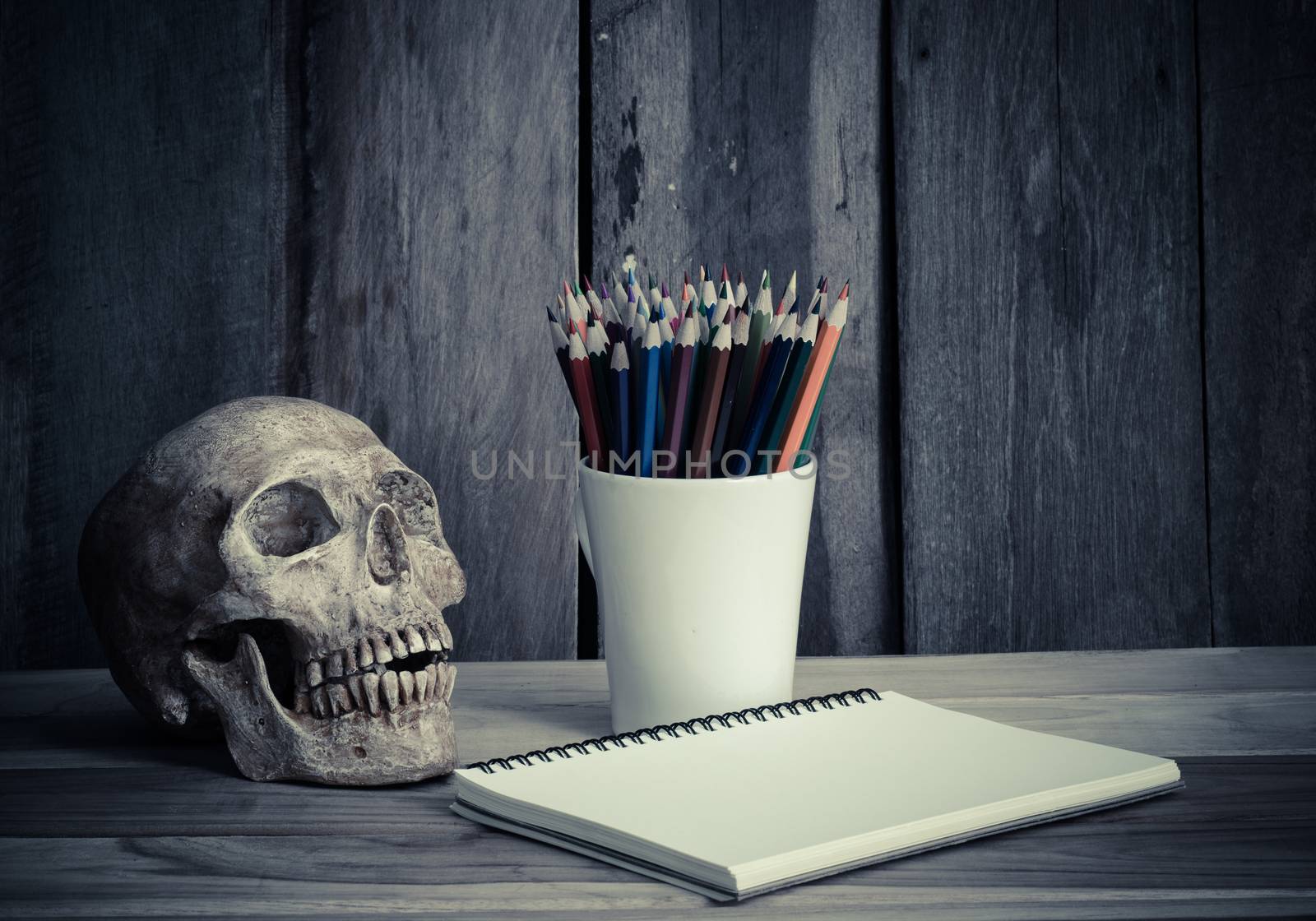 still life skull ,sketchbook and color pencil on wooden background by photobyphotoboy