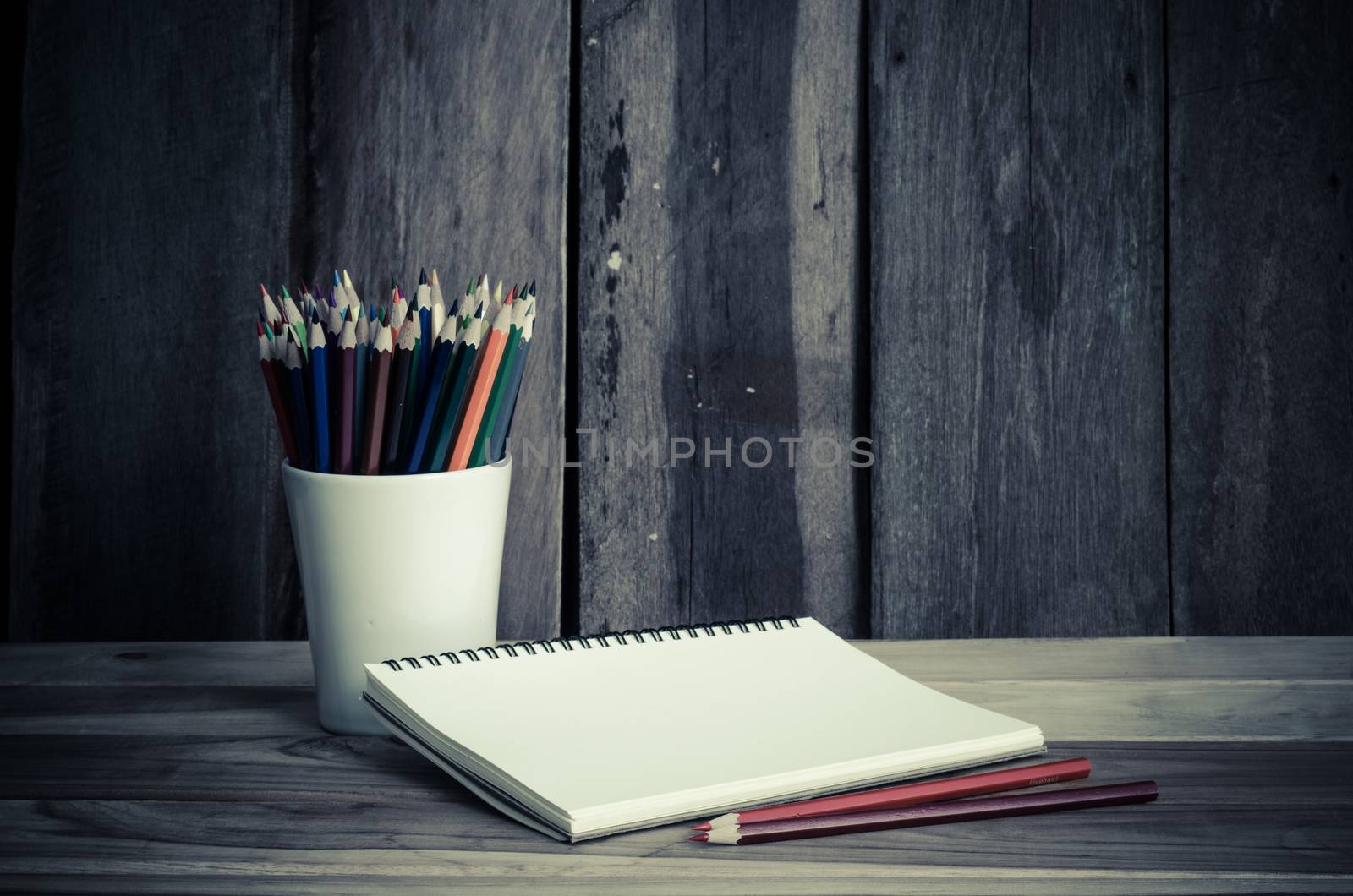 Color pencil and sketchbook on wood table