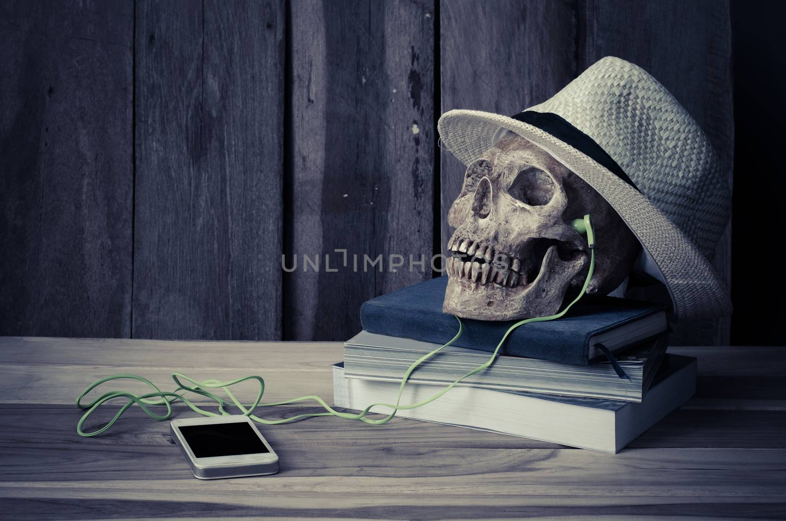 still life - skull have headphone on books and hat on wooden table by photobyphotoboy