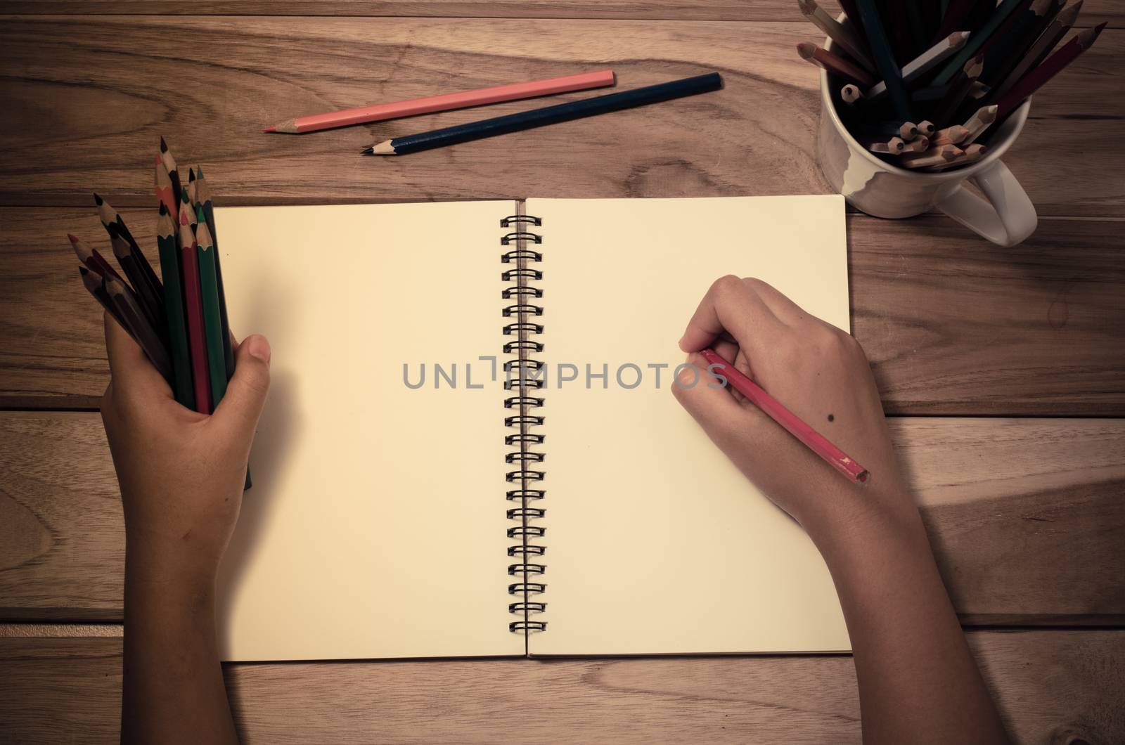 Hand-written note in pencil on a wooden table - hand focus by photobyphotoboy