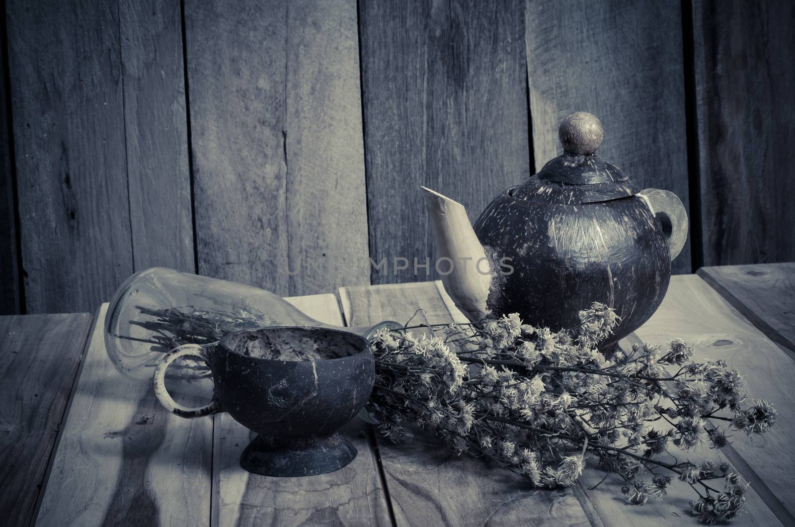 Kettle glass of water from coconut shells, dried flowers.on wooden background