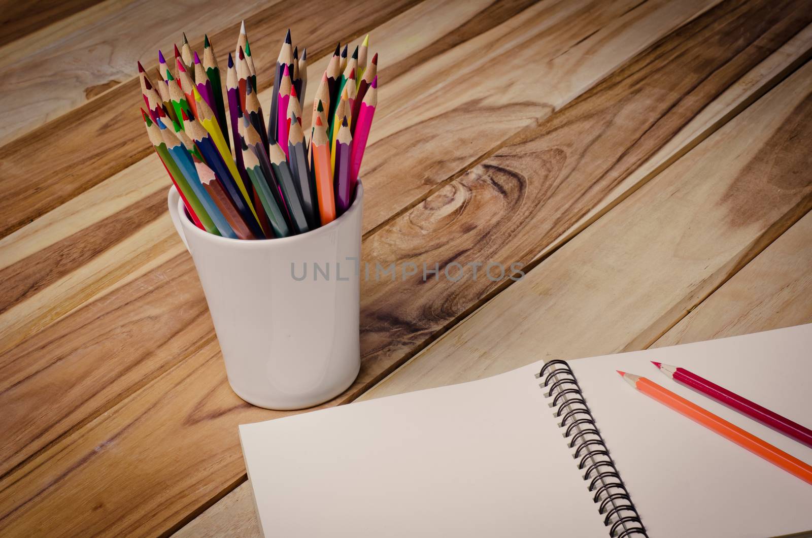 Color pencil and sketchbook on wood table by photobyphotoboy