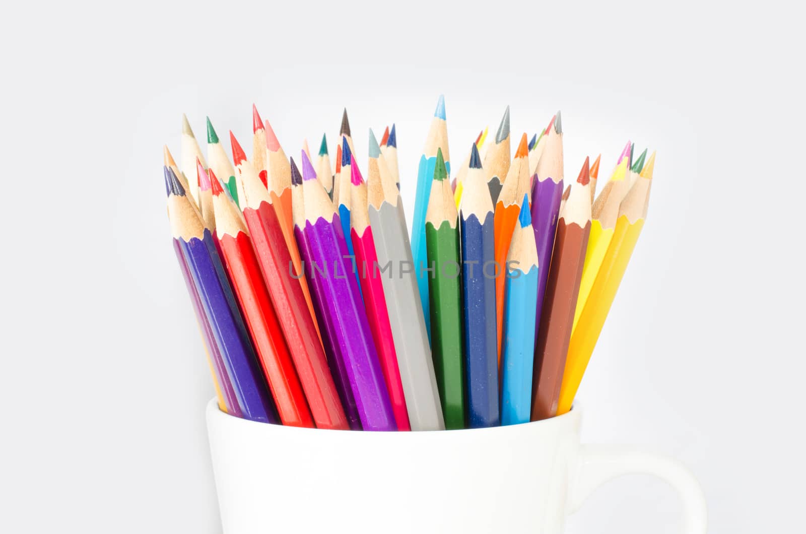 Stack of colored pencils in a glass on white background