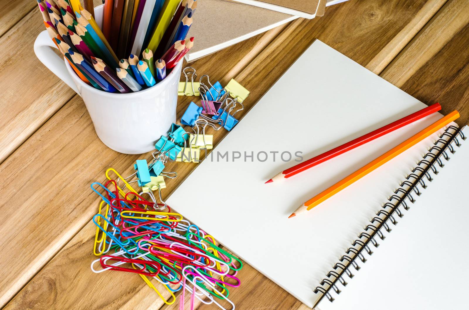 Colored pencils and notebook paper clip turnovers on a wooden table.