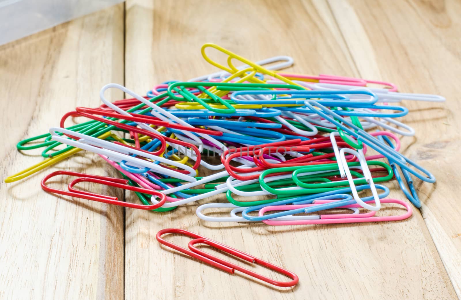 Colorful paper clips on a wooden table.