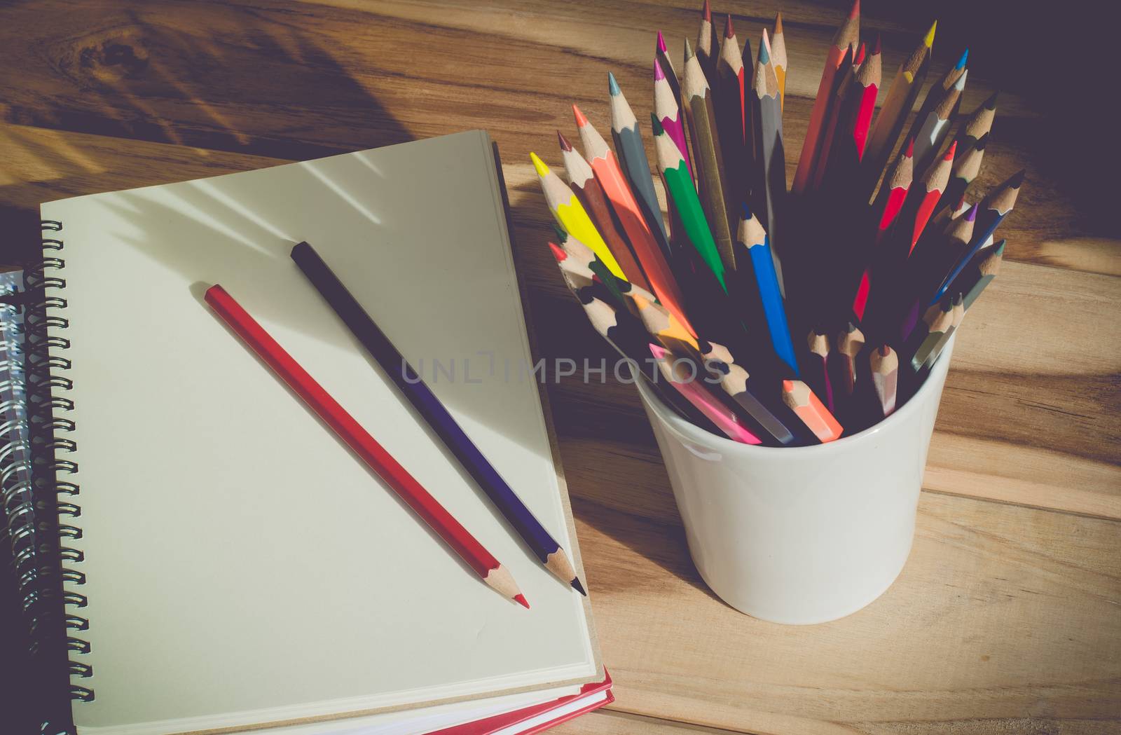 Color pencil and sketchbook on wood table