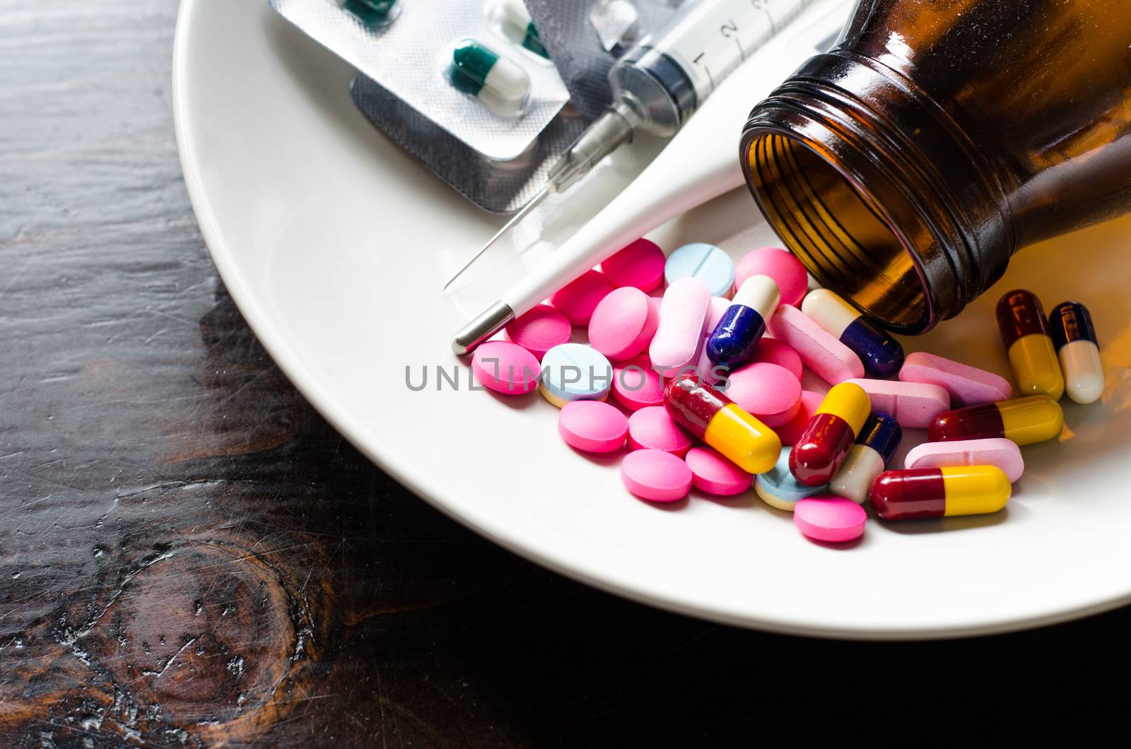 Various types of medicines, syringes and thermometers. In white dish concept of some people who need medicines instead of eating.