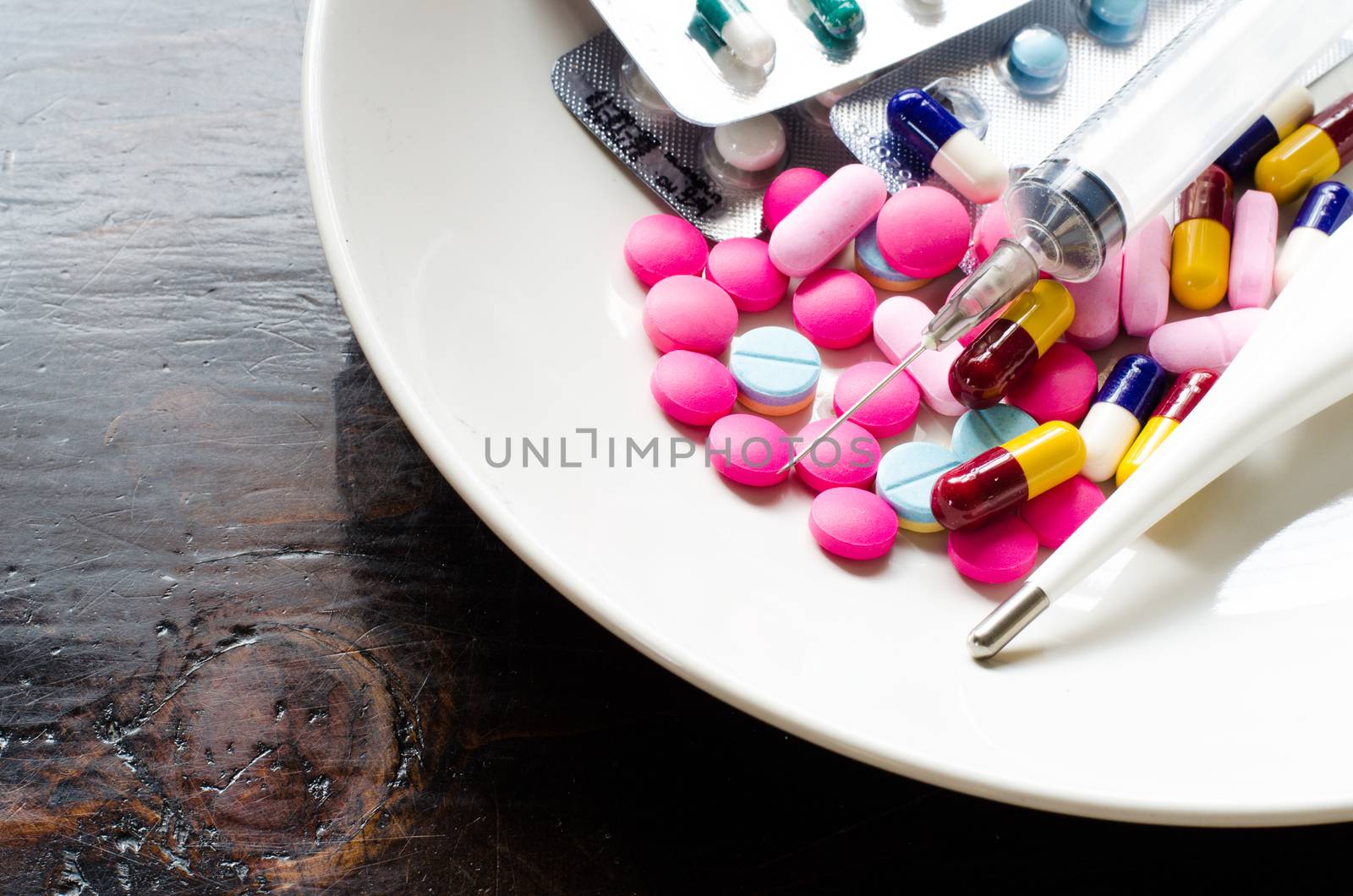 Various types of medicines, syringes and thermometers. In white dish concept of some people who need medicines instead of eating.