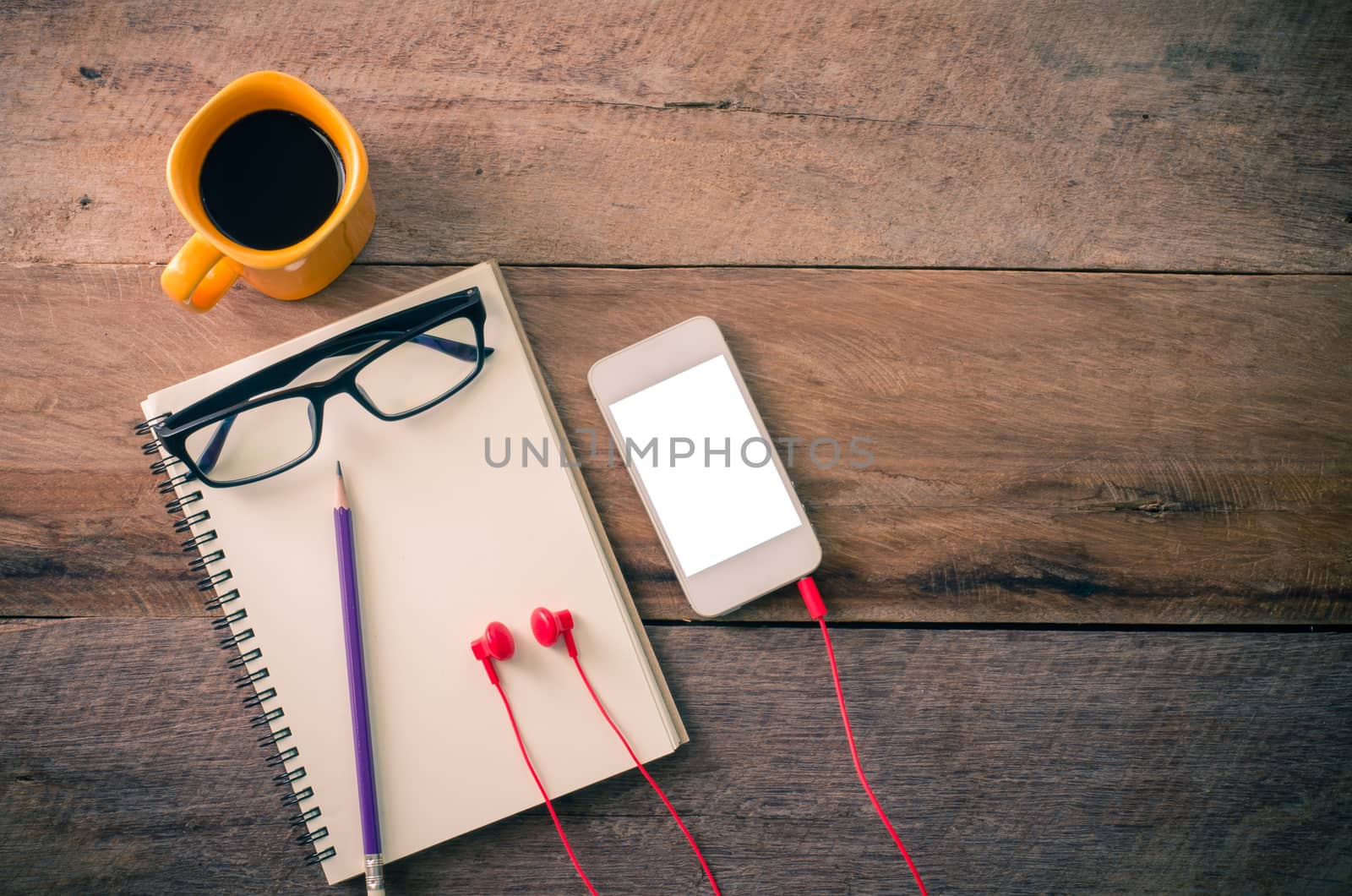surface of a wooden table with notebook, smartphone, glasses,