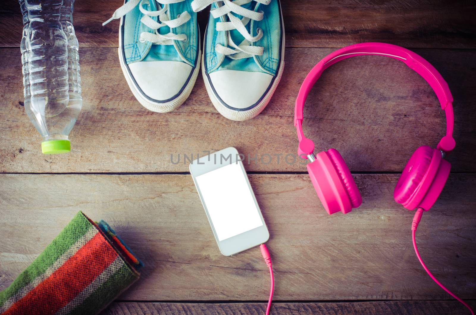 Shoes, water bottles headset smart phone scarf on a wooden table ready to depart.