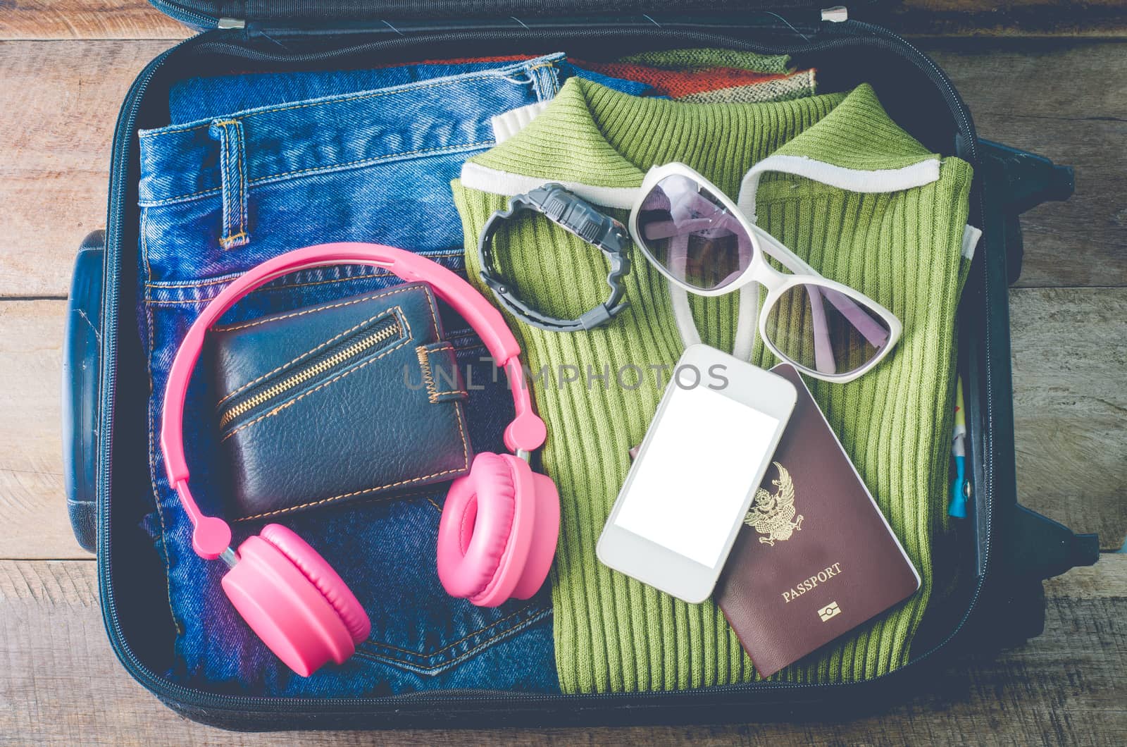 Clothing traveler's Passport, wallet, glasses, watches, smart phone devices, on a wooden floor in the luggage ready to travel.
