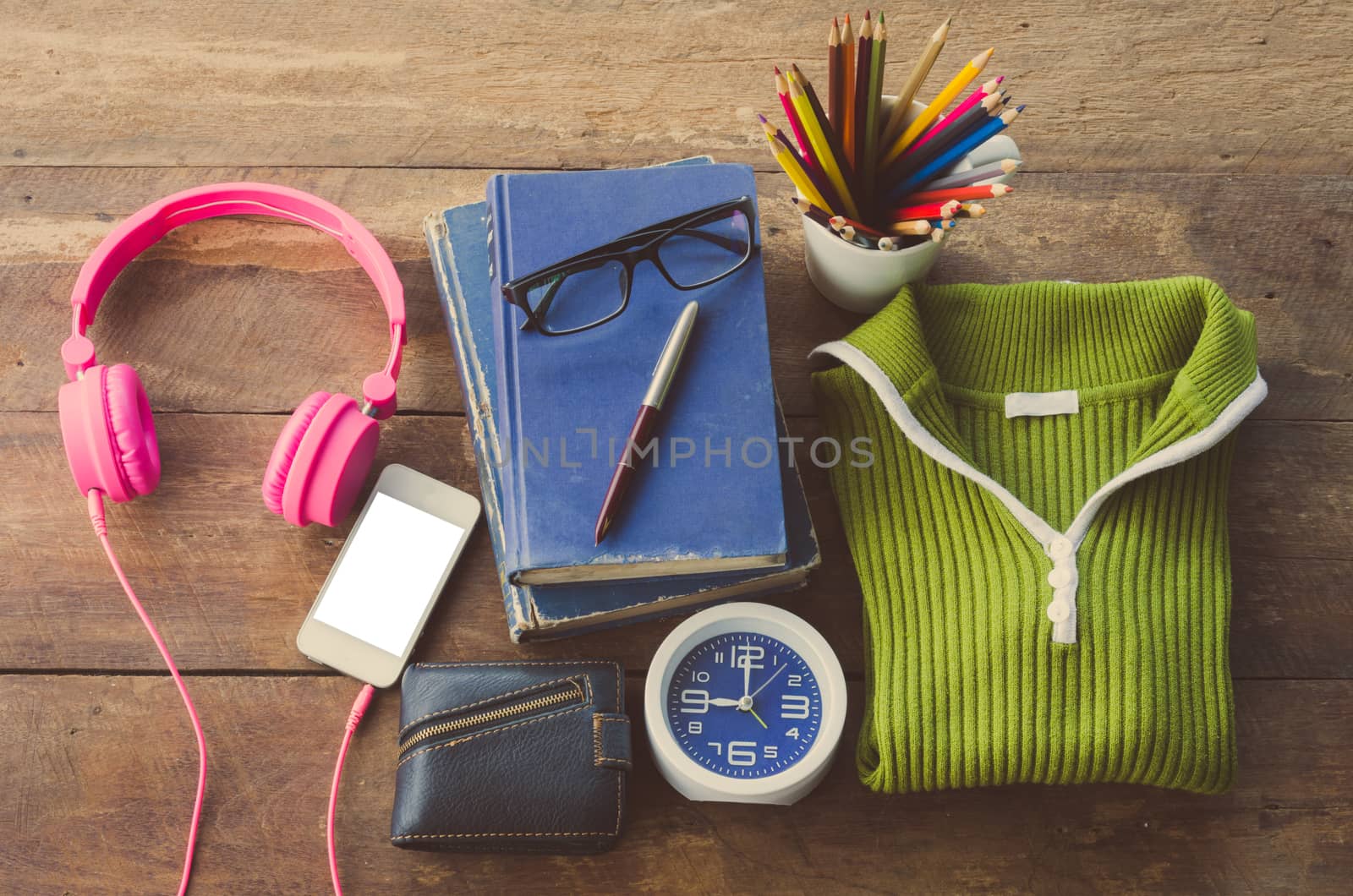 Accessories, sweaters, books, pens, glasses, colored pencils, clocks, smart phones, put on a wooden table