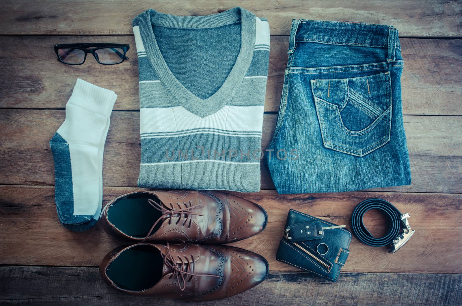 Sweaters, jeans, socks, shoes, belts, wallets, sunglasses, ready for travel.