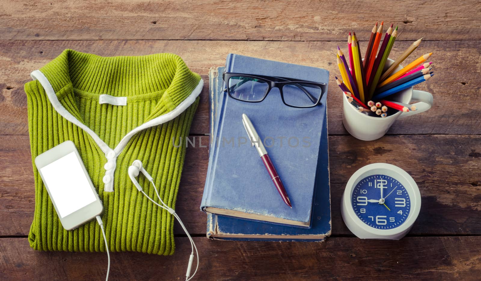 Accessories, sweaters, books, pens, glasses, colored pencils, clocks, smart phones, put on a wooden table