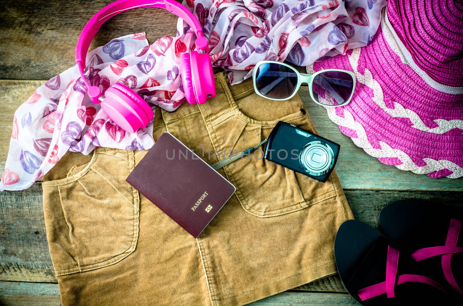 Travel accessories, headphones, camera, glasses, scarves, skirts, shoes, hat in preparation for the trip.