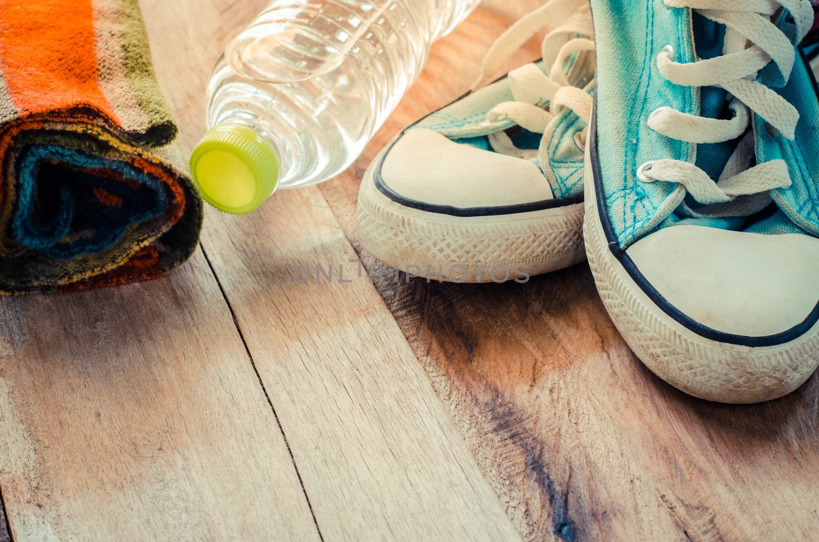 accessory scarves, shoes, water bottles placed on a wooden floor.