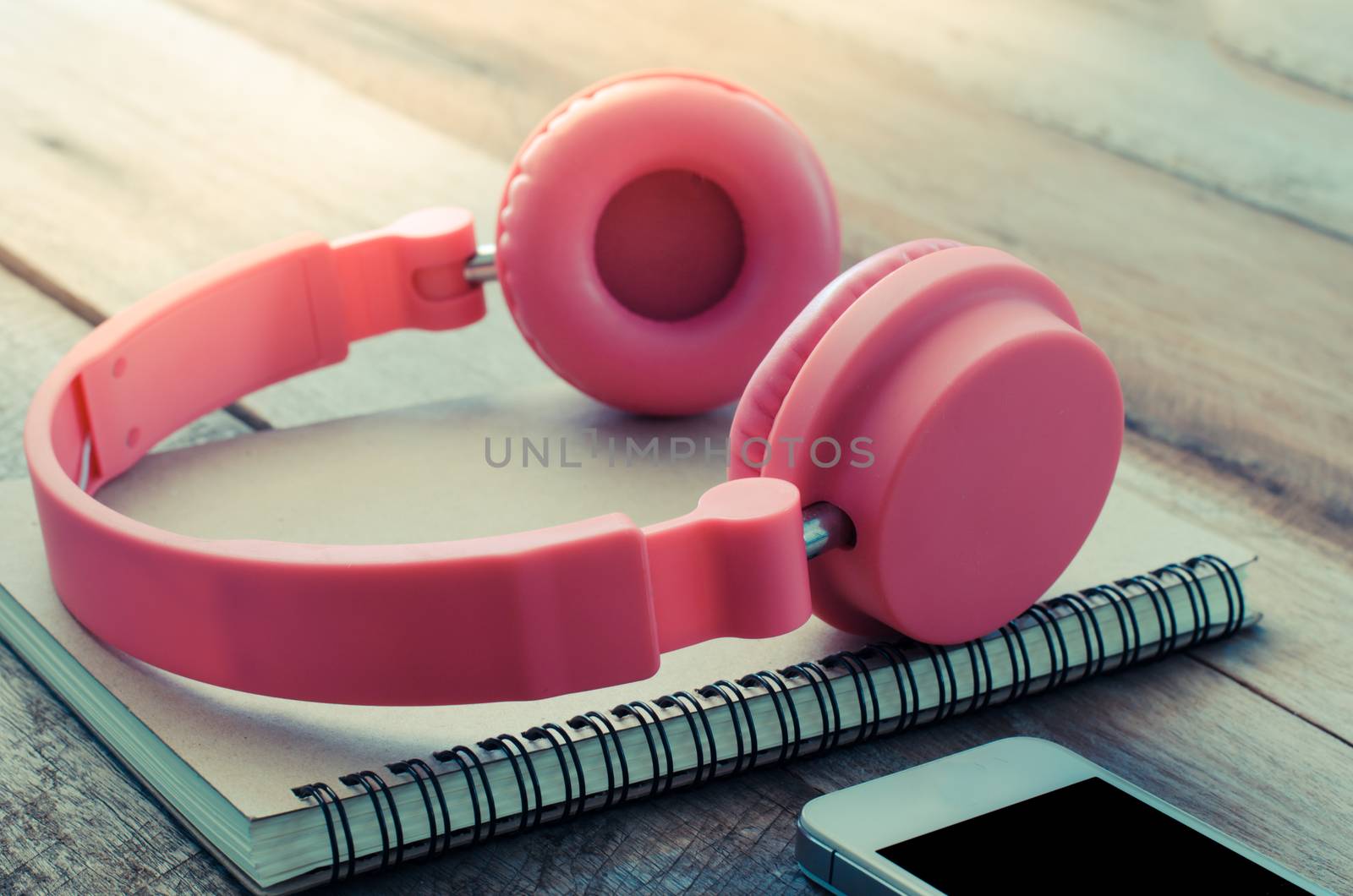Earphone Pink put on notebooks and smartphones on wooden floor morning light