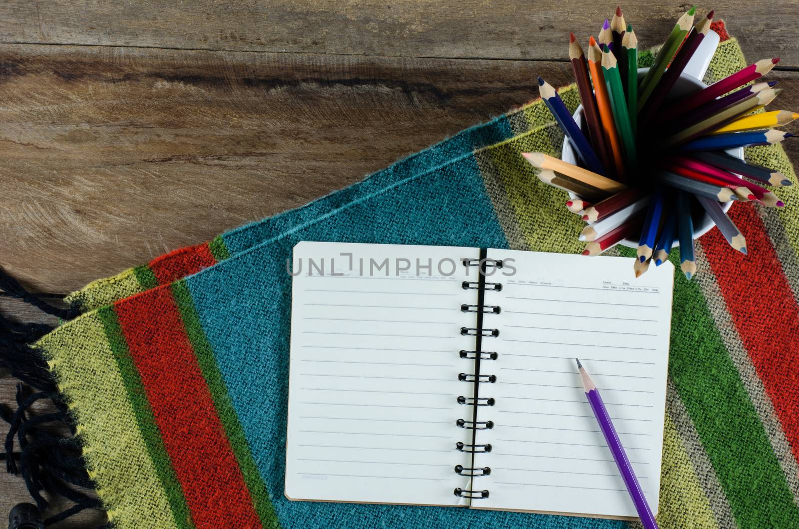 Notebooks, pencils fabric on a wooden table.