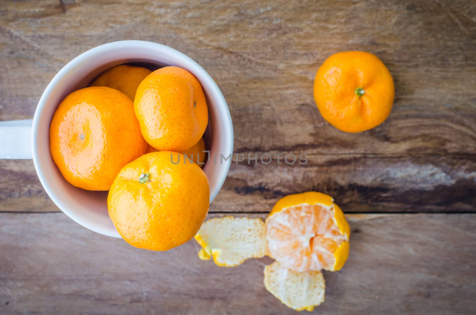 Orange in a glass cup on a wooden floor.