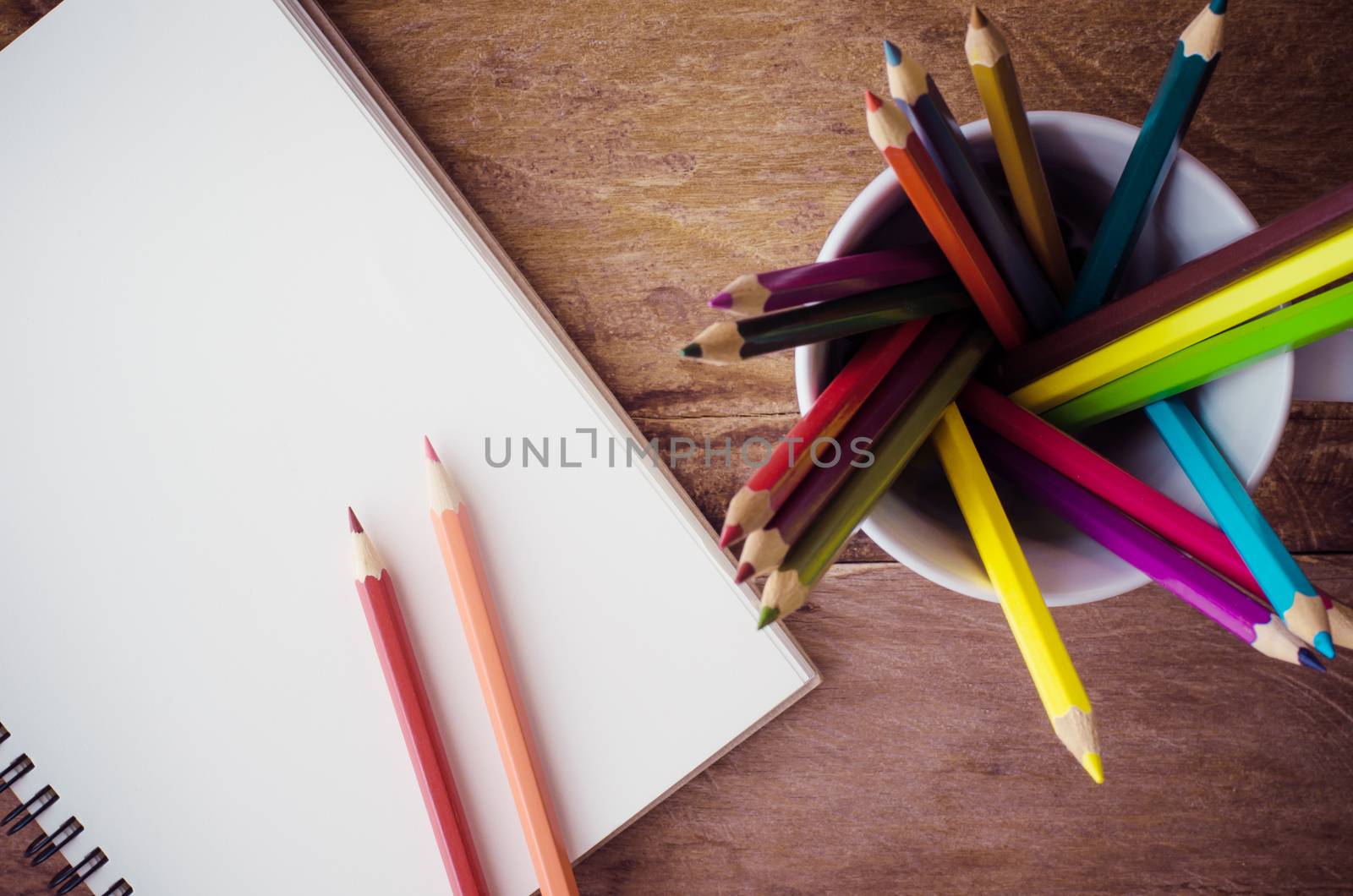 Color pencil and sketchbook on wood table