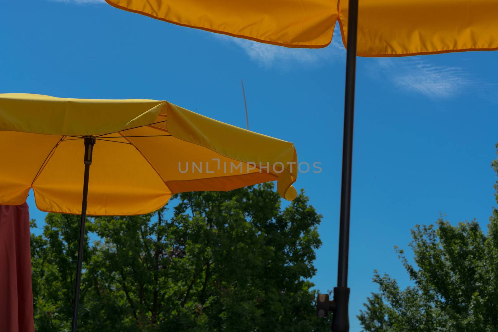 Two yellow parasols with bright sun and blue sky