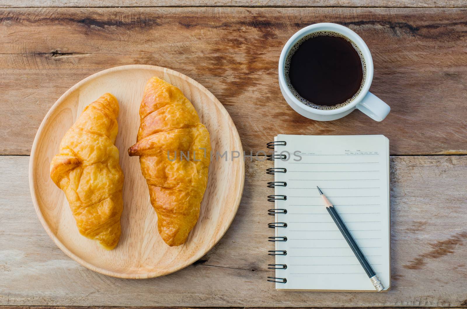 Croissants coffee notebook and pencil on the wooden table - tone vintage