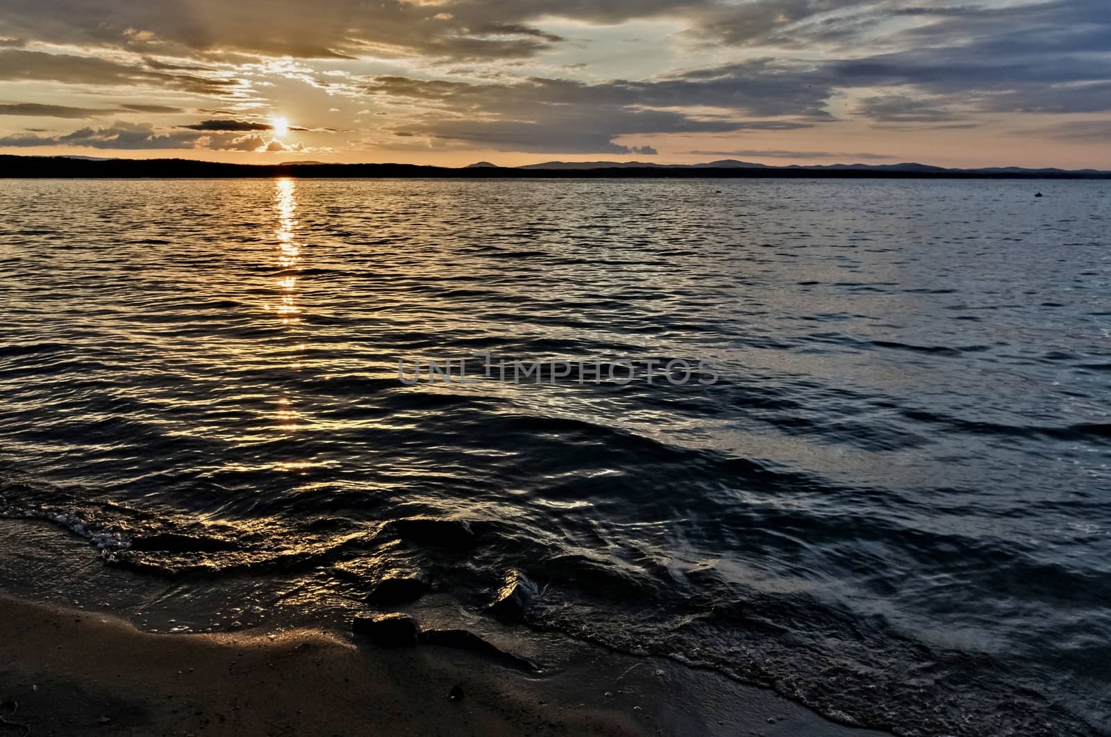 Golden sun sinks over the lake in the evening, golden water, South Ural lake Uvildy