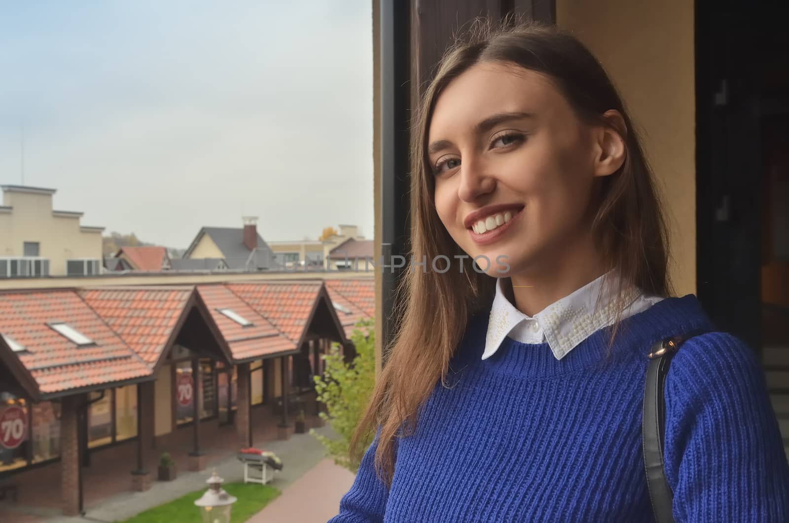 Portrait of a beautiful girl in a blue sweater against the background of Austrian architecture