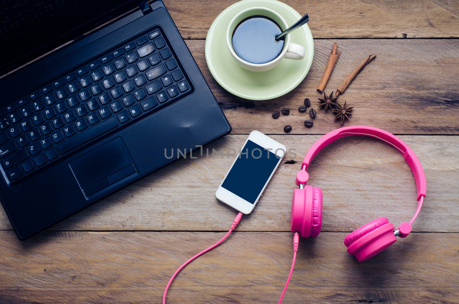 Coffee cup, notebook, headphone and smart phone on the wooden floor in the morning.