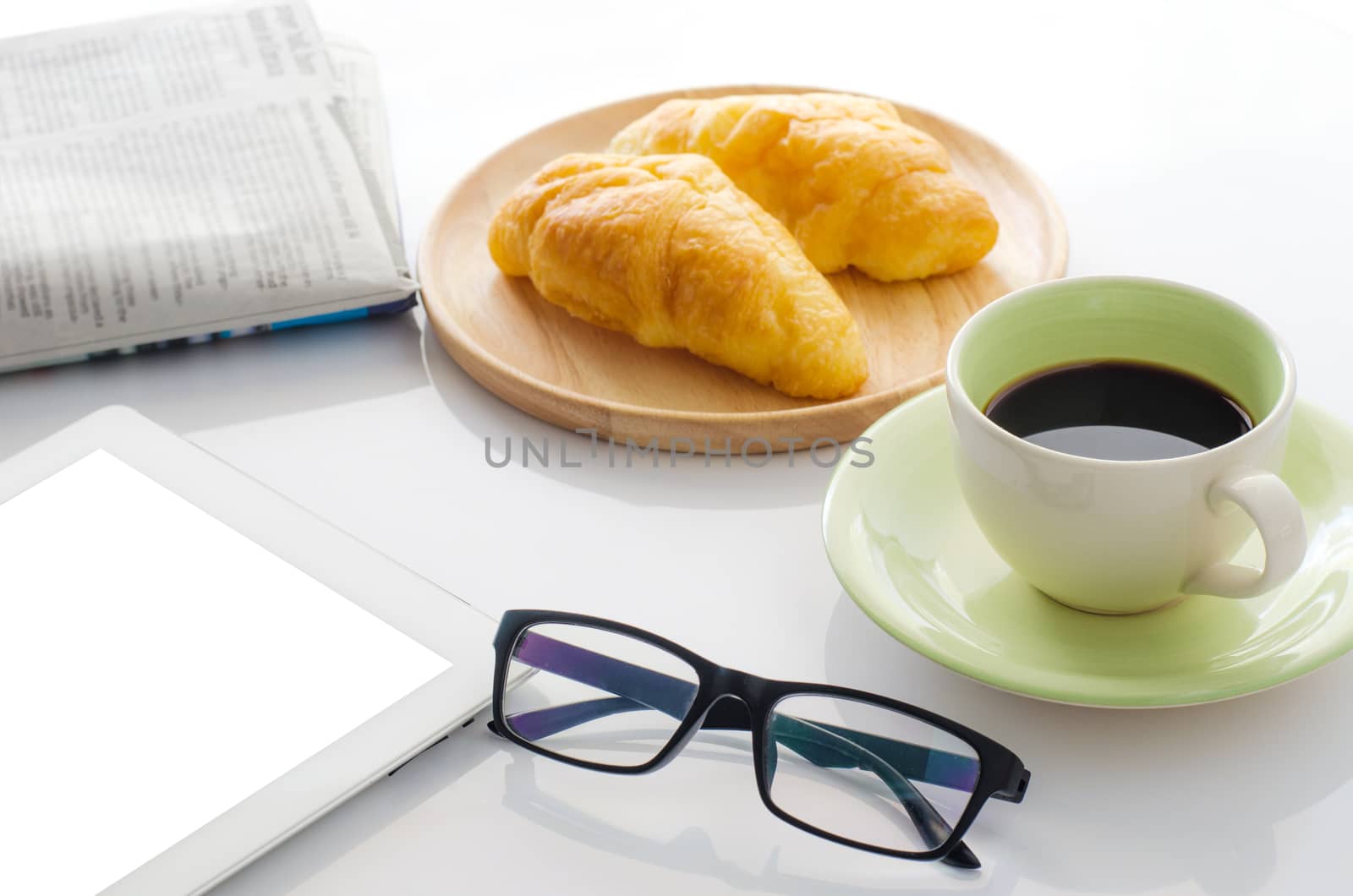 Glasses on the desk with smartphone, croissants, Newspaper and coffee cup.in the morning by photobyphotoboy