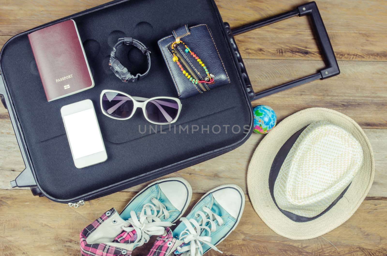 Clothing traveler's Passport, wallet, glasses, watches, smart phone devices, hat, shoes, on a wooden floor on the luggage ready to travel. by photobyphotoboy